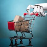 Robot arm holding shopping cart with cardboard boxes.