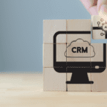 Hand holding wooden cube puzzle with AI-CRM icon on grey background.