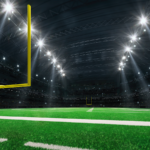 American football stadium with yellow goal posts, grass field and fans at playground view.
