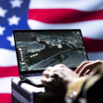 Soldier using a laptop running a military software on a background of the US flag.