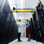 IT professionals shaking hands on a server room hallway.