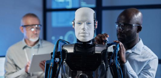 Two engineers adjusting a humanoid robot.
