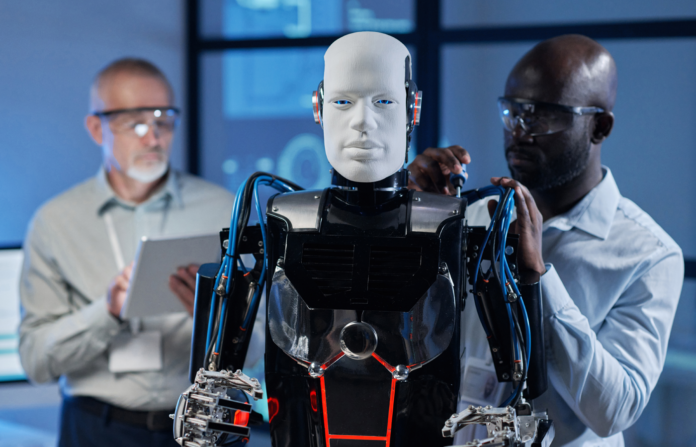 Two engineers adjusting a humanoid robot.