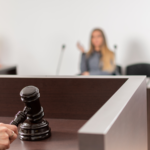 Close up shot of a judge's hand with a gavel in a court room hearing.