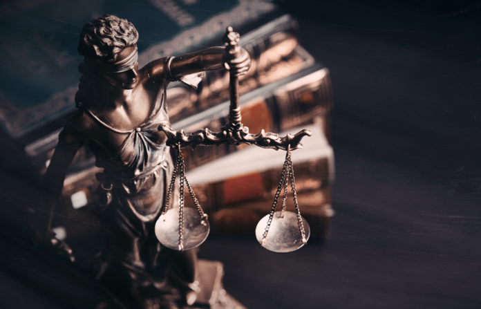 Statue of Lady Justice with law books in the background.