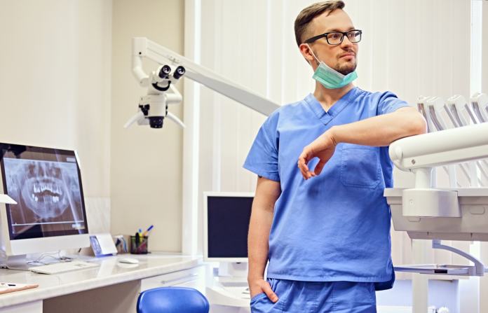 Dentist in a room with medical equipment on the background.