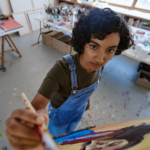 Top view of a woman painting on a canvas.