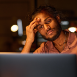 Tired programmer working over a new software on a laptop.