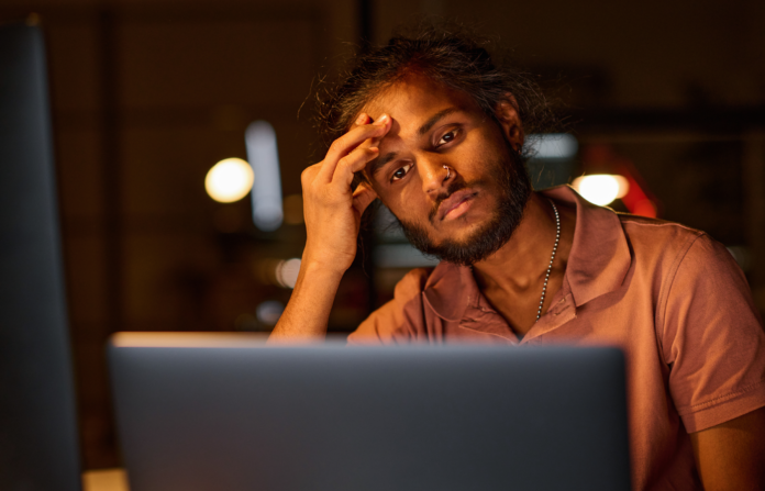 Tired programmer working over a new software on a laptop.