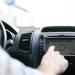 Man interacting with the dashboard infotainment screen inside a car.