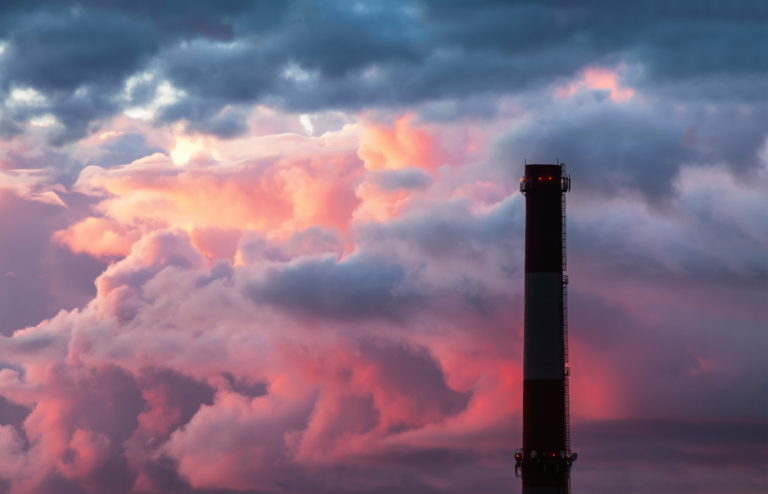 Industrial chimney stack silhouette against a cloudy sky background.