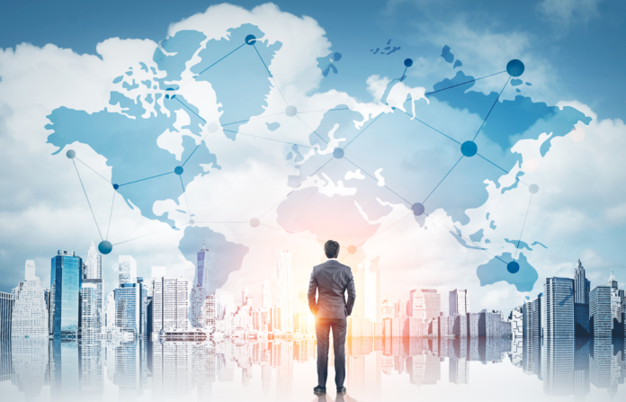 Businessman looking towards an abstract background of the world map and city scape.