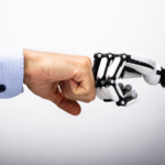 Human and robot hand making a fist bump.