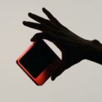 Semi silhouette of a hand holding a device.