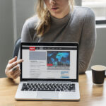 Blond woman pointing at a laptop screen