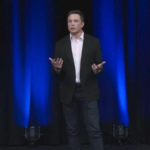 A photo of Elon Musk speaking on a stage.