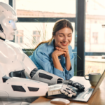 Robot and woman working on laptop in office.