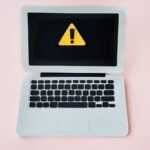 Stock photo of a laptop with a warning indicator on the screen.