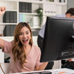 Female employee raising hands happy and laugh for receiving good news.