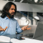 An employee getting frustrated in front of his laptop.