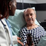 Stock photo of man in a hospital bed listening to a doctor.