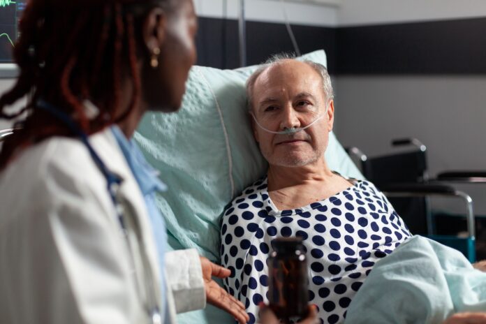 Stock photo of man in a hospital bed listening to a doctor.