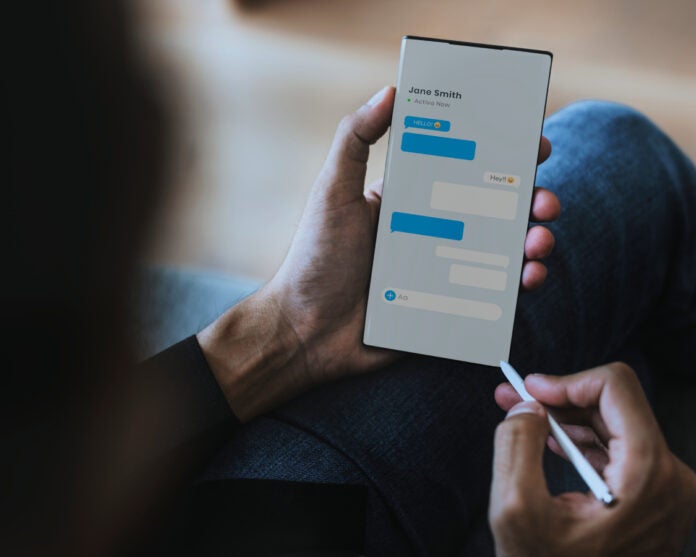 A person texting on smartphone with stylus pen.