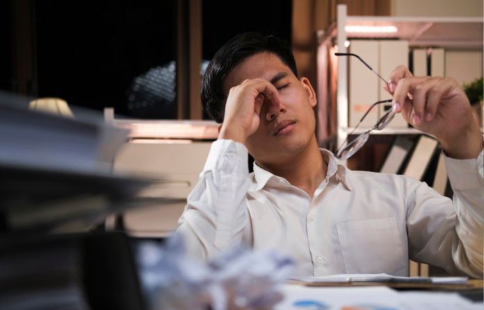 Exhausted young man with laptop in office.