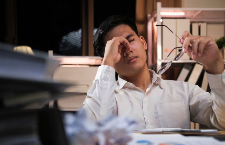 Exhausted young man with laptop in office.