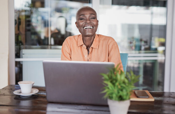beautiful-mature-african-woman-sitting-in-a-bar-ou-2025-03-10-13-07-10-utc (1) Woman sitting in a bar outdoor and working with laptop.