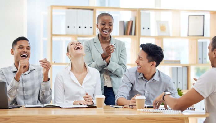 Office workers laughing together in meeting.