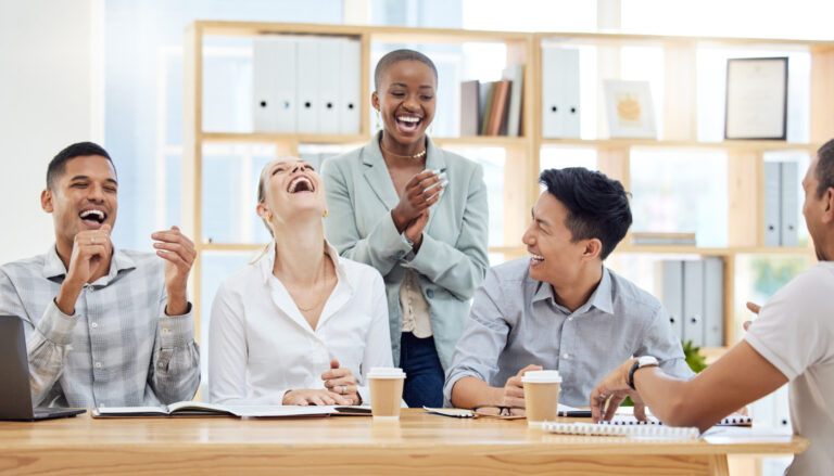 Office workers laughing together in meeting.