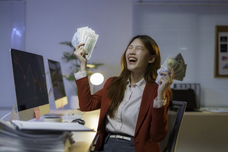 Stock photo of a businesswoman celebrating with cash in her hands.