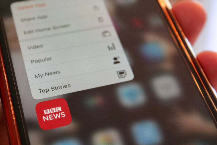 rich-smith-qezGbhOzQyg-unsplash (1) A close up of a person holding a cell phone with the BBC News app.