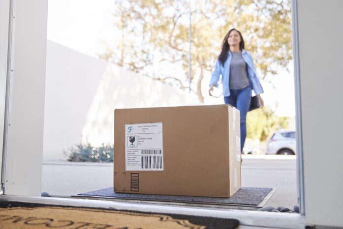 Stock photo of a woman coming home to a delivered package.