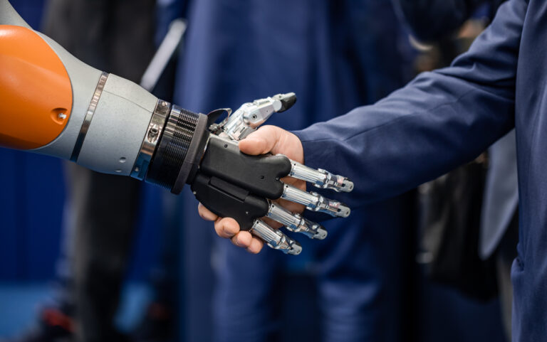 Hand of a businessman shaking hands with a Android robot.