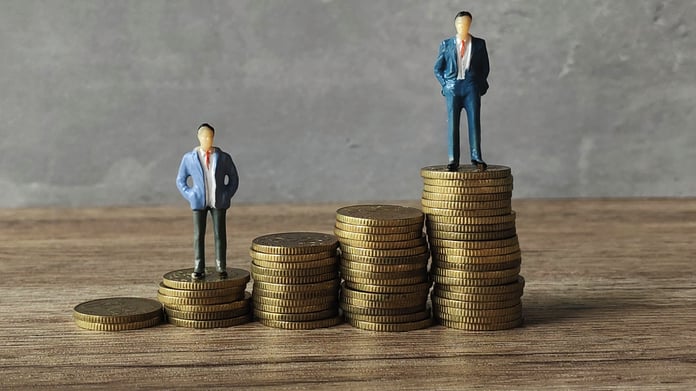 Miniature businessmen standing on stack of coins.