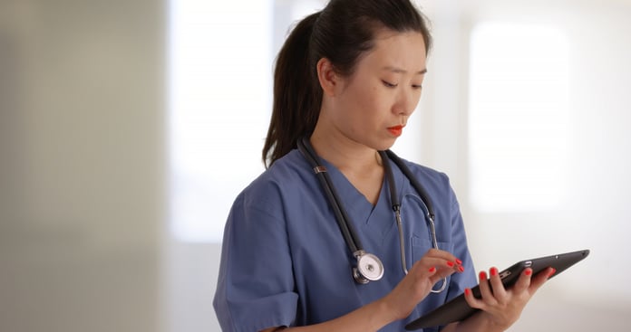 Professional young doctor or nurse using portable tablet inside hospital